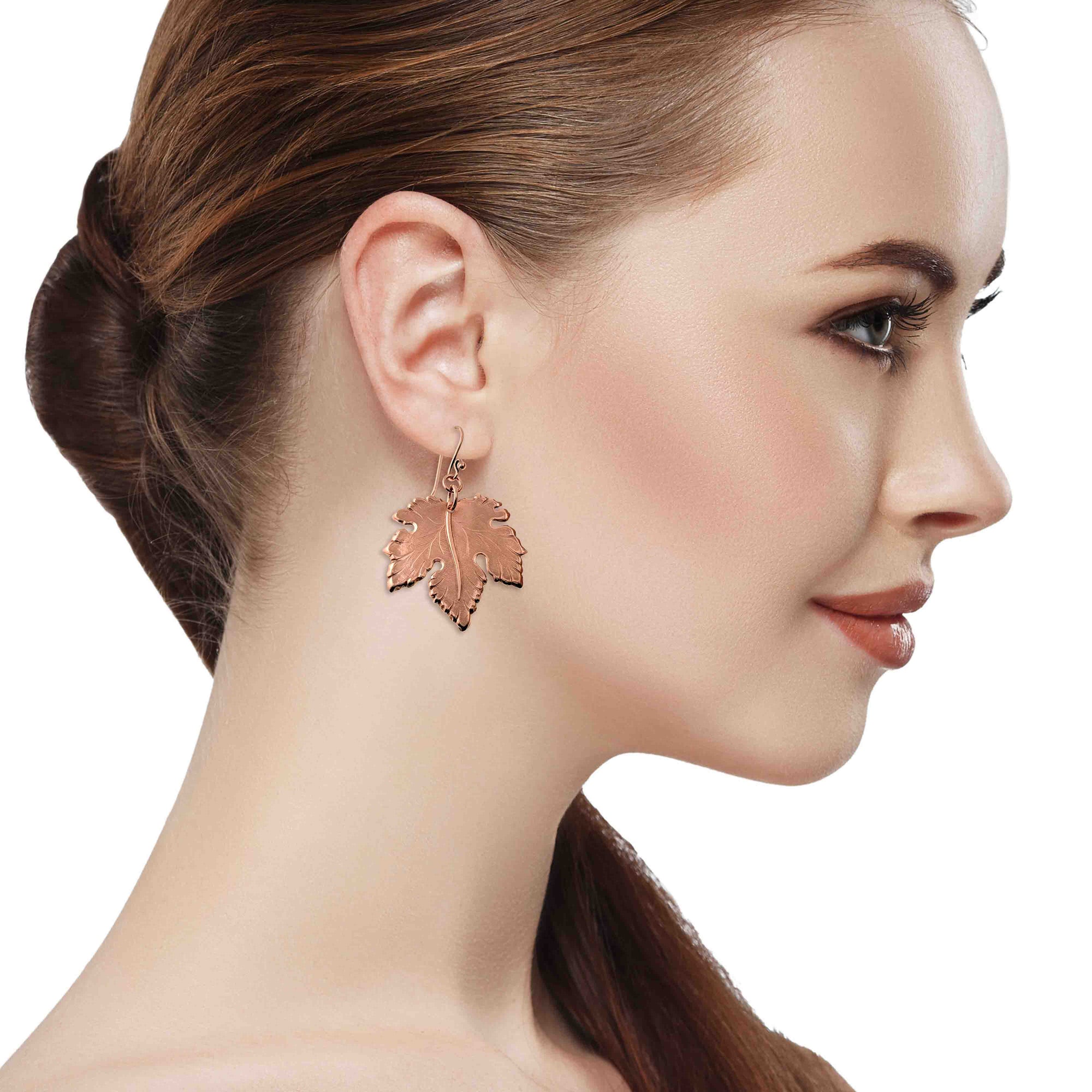Woman wearing a pair of Large Maple Leaf Copper Dangle Earrings  on a white background