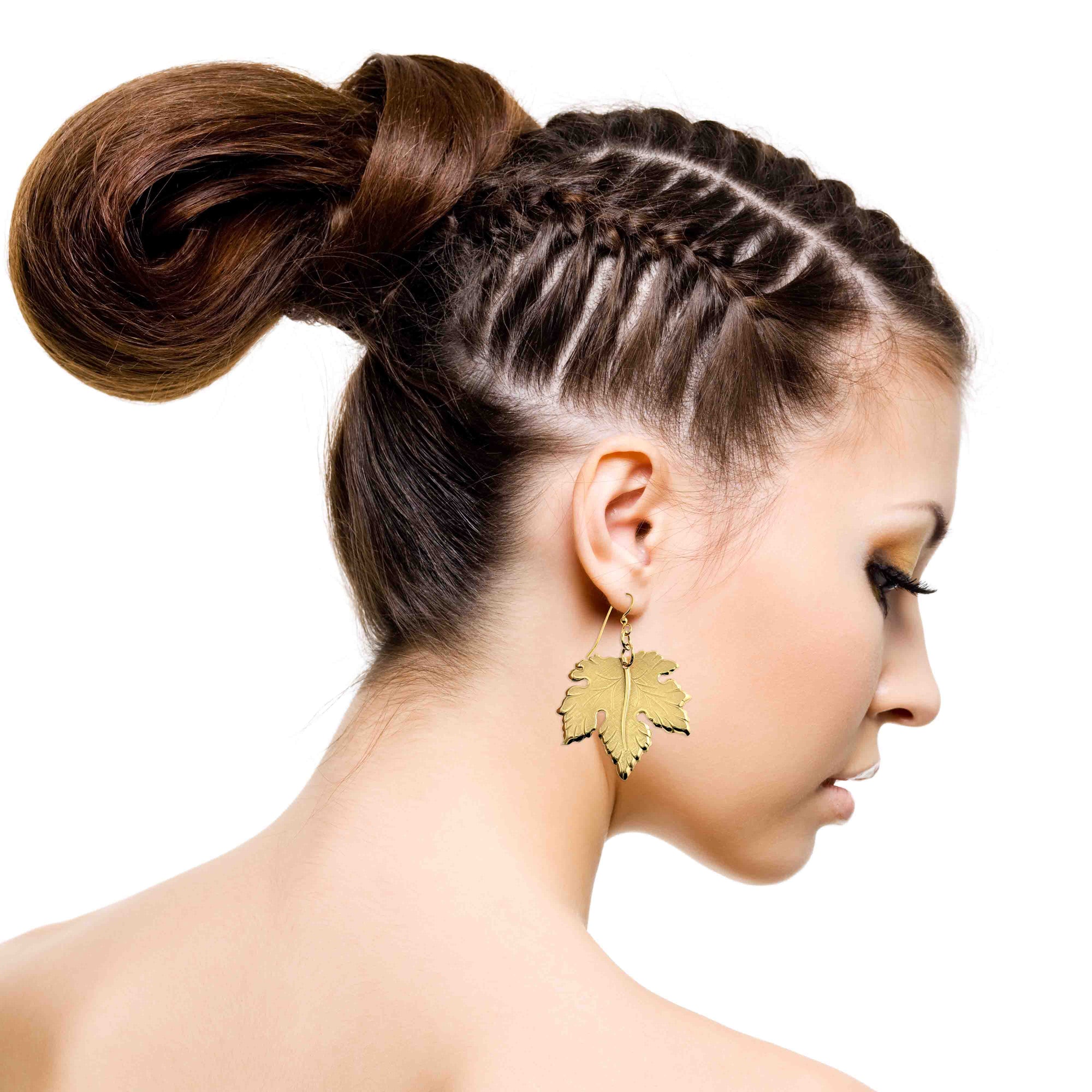 Woman with braided hair styled in a bun, wearing Large Maple Leaf Nu Gold Brass Dangle Earrings on a white background