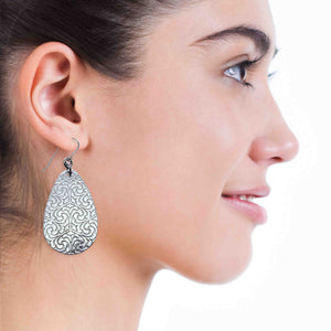 4 of 8: A Smiling Woman Wearing Damask Embossed Large Aluminum Teardrop Earrings