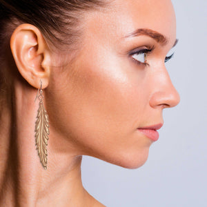 6 of 7: Glamorous Woman Wearing Long Feather Copper Drop Earrings