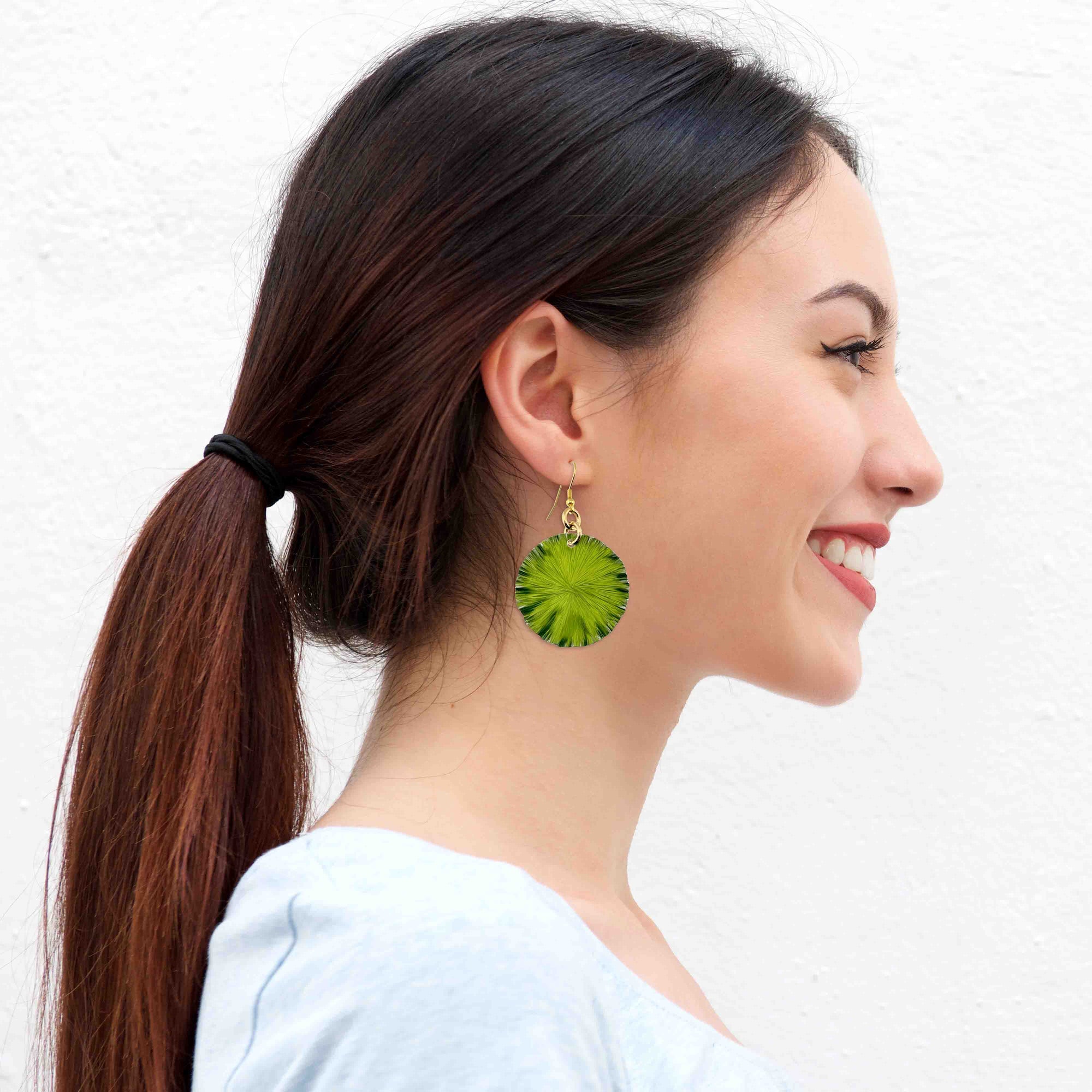 A Smiling Woman Wearing Medium Lime Anodized Aluminum Lily Pad Earrings 