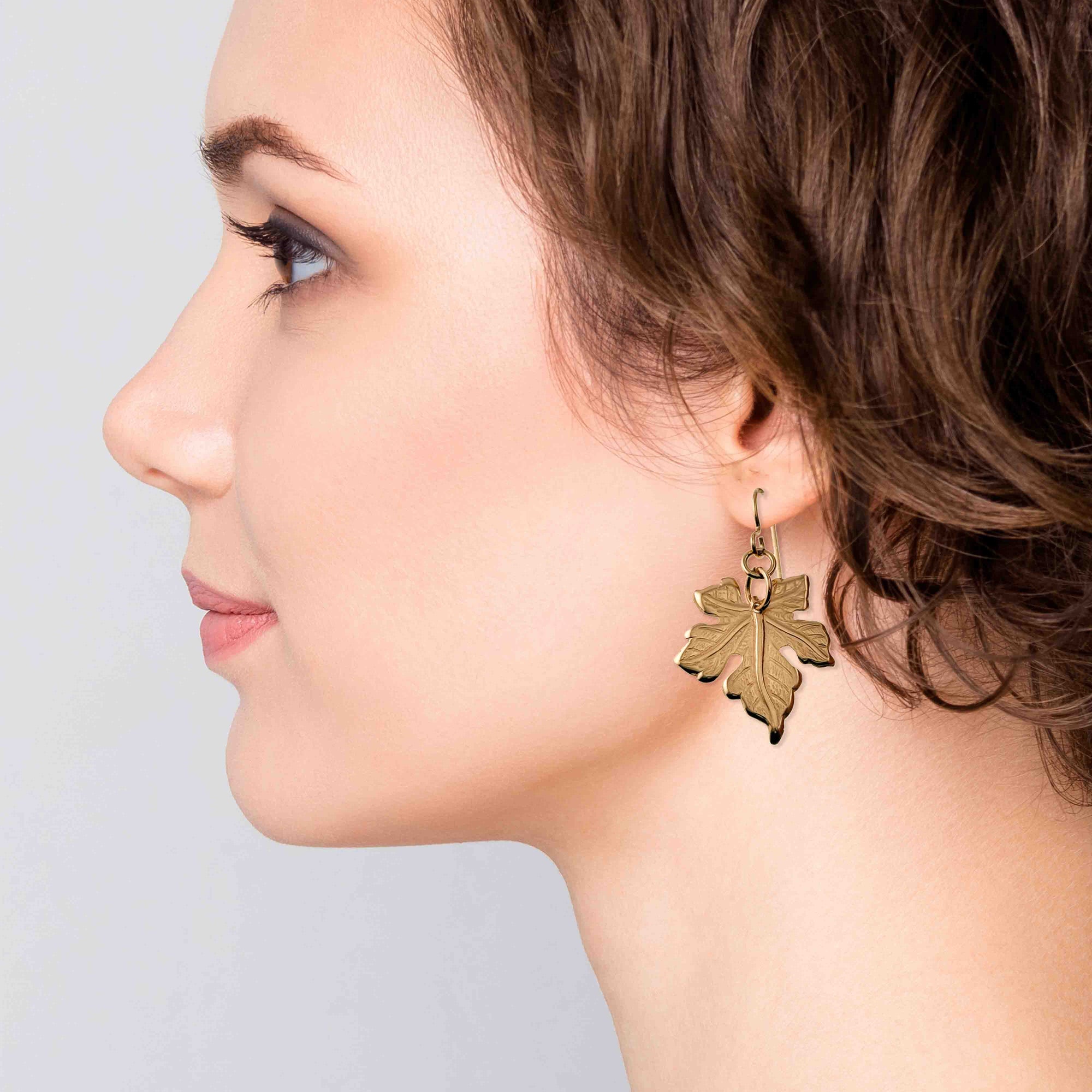 Woman wearing a Medium Maple Leaf Bronze Dangle Earring against a light background