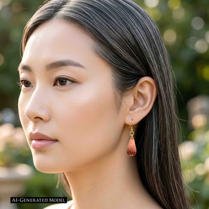 4 of 7: AI generated model wearing a Mini Hammered Copper Teardrop Earring with brass French ear wire. The petite copper drop rests below the earlobe and shows its warm hammered finish. The model has long dark hair worn behind the ear, with soft natural light and a blurred green outdoor background.