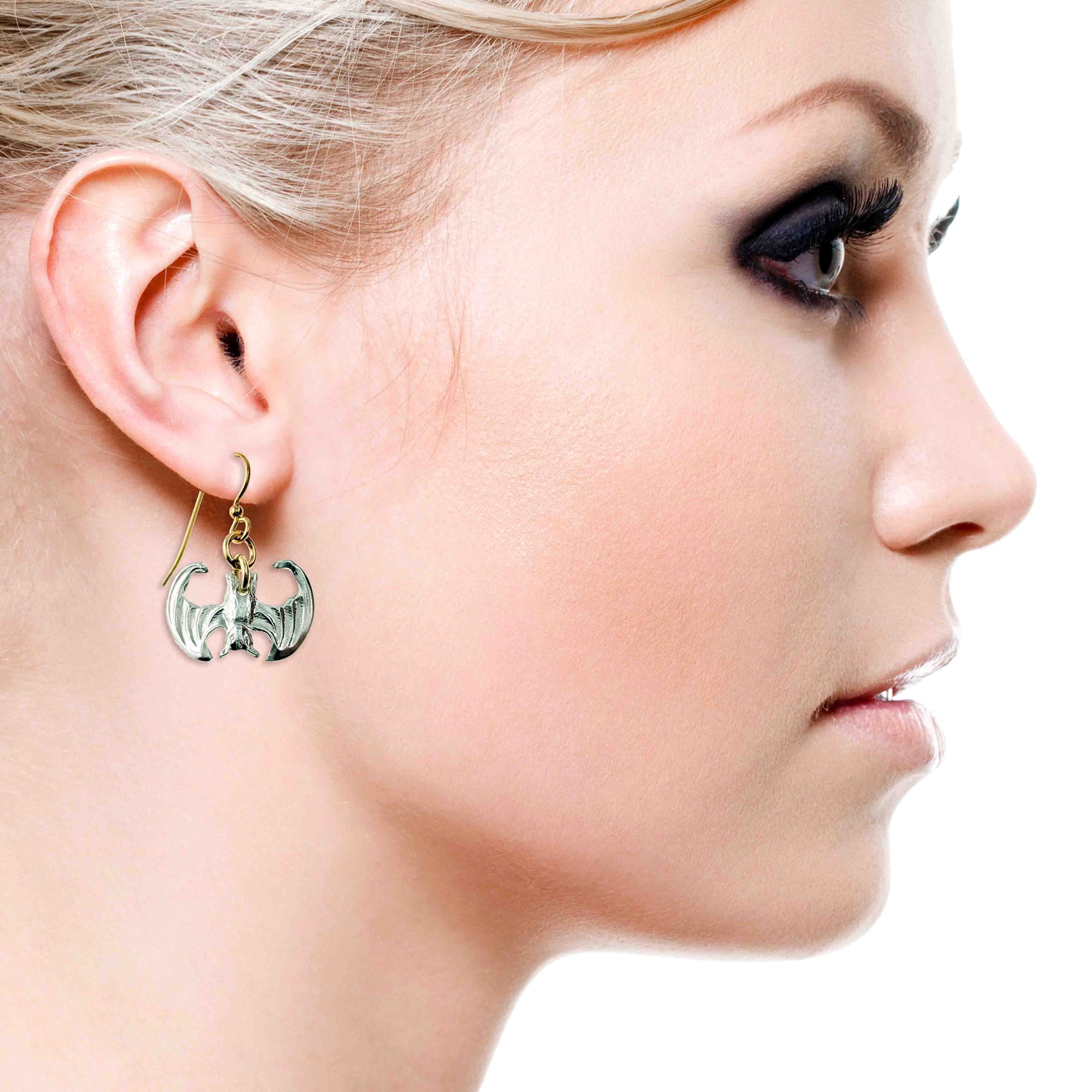 Close-up of a woman wearing a bat-shaped earring on a white background