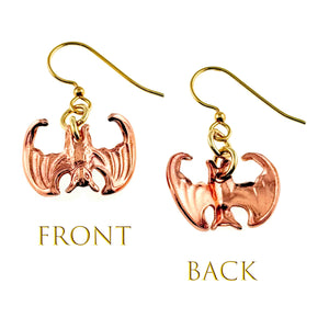 3 of 7: Image showing a pair of handcrafted copper vampire bat dangle earrings displayed side by side, with the left earring showing the detailed front with textured wings and body, and the right earring showing the smooth back, both hanging from brass French ear wires, labeled “Front” and “Back” below each earring.