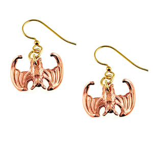 1 of 7: Close-up image of a pair of handcrafted copper dangle earrings shaped like miniature vampire bats with outstretched wings, featuring detailed die-struck textures and hanging from brass French ear wires.