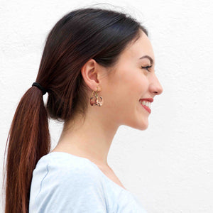 4 of 7: Side profile of a smiling woman with dark hair in a ponytail wearing handcrafted copper vampire bat dangle earrings with brass French ear wires, set against a plain white background.