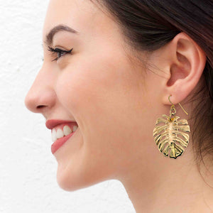 6 of 6: A Smiling Woman Wearing Monstera Nu Gold Brass Leaf Earrings