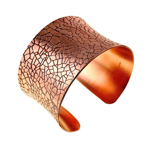 3 of 9: Reverse angled view of the Mosaic Embossed Anticlastic Copper Cuff Bracelet on a white background. The wide brushed copper surface displays an irregular tile pattern with dark recessed lines. The sculpted cuff curves around an open center with softly rounded ends.
