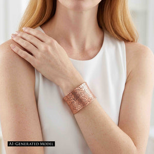 8 of 9: Fair skinned woman with long red hair wearing the wide mosaic embossed copper cuff on her wrist with a sleeveless white top. Her crossed arm pose shows the bracelet from the front and gives a clear sense of its one and one half inch width. A black label identifies the model as AI generated.