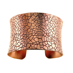 5 of 9: Front product view of the Mosaic Embossed Anticlastic Copper Cuff Bracelet on a white background. The wide copper face shows an irregular tile pattern with dark recessed lines and a brushed matte finish. The curved edges and open ends reveal the sculpted anticlastic form.