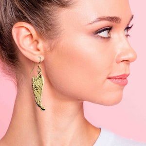 2 of 7: Woman wearing Nu Gold Brass Guardian Angel Wing Drop Earrings  against a pink background