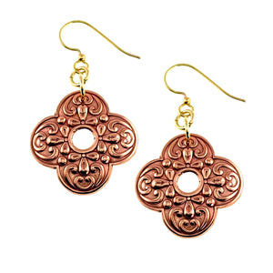 1 of 7: Ornate clover-shaped copper drop earrings with polished scrollwork detailing and a small center cutout. Warm raw copper finish paired with gold tone brass French ear wires, shown on a clean white background.