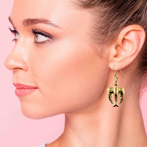 2 of 7: Woman wearing a handcrafted Nu Gold brass peace dove dangle earring with a detailed design and French ear wire, shown against a soft pink background.