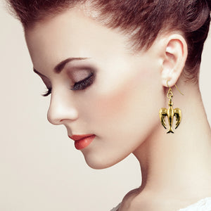 4 of 7: Woman wearing a handcrafted Nu Gold brass peace dove dangle earring, featuring a detailed bird design with a golden finish, shown against a soft neutral background.