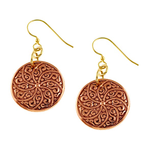 1 of 8: Pair of Small Copper Mandala Disc Earrings photographed on a white background. Each round copper disc features a swirling floral style mandala pattern with raised polished details and darker recessed areas. Brass French ear wires and connecting rings add a warm gold tone above the copper discs.