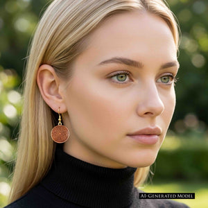 7 of 8: AI Generated Model wearing a Small Copper Mandala Disc Earring with a black turtleneck outdoors. The round copper disc hangs from a brass French ear wire and displays the swirling mandala pattern. The model has straight blonde hair, with soft daylight and a blurred green garden background.