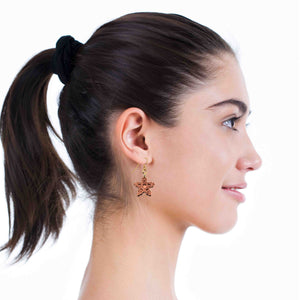 6 of 7: Close-up of a woman's profile wearing a Small Copper Snowflake Dangle Earring on a white background