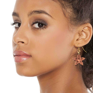 4 of 7: Close-up of a woman wearing a Small Copper Snowflake Dangle Earring on a white background