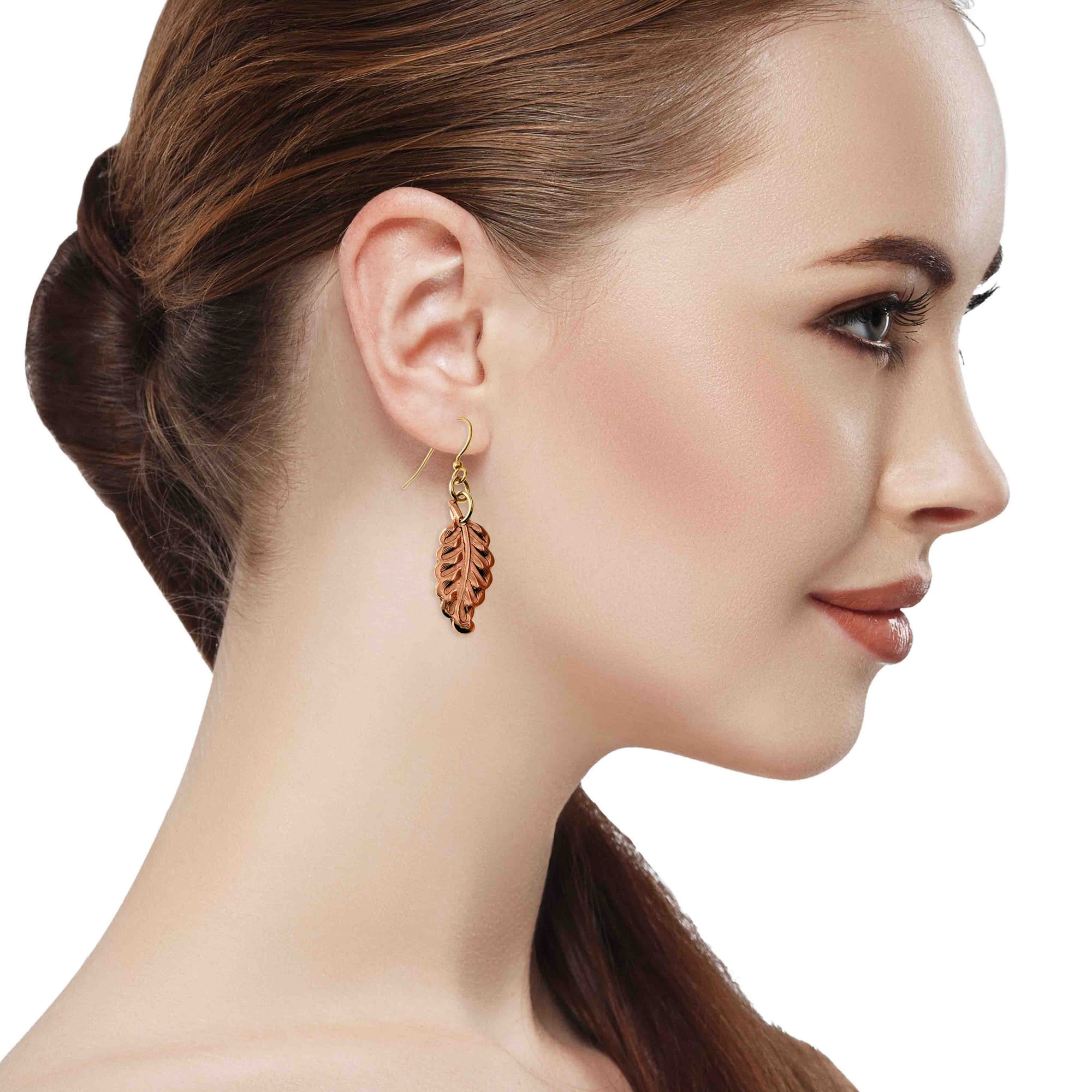 Woman wearing Small Feather Copper Dangle Earrings on a white background