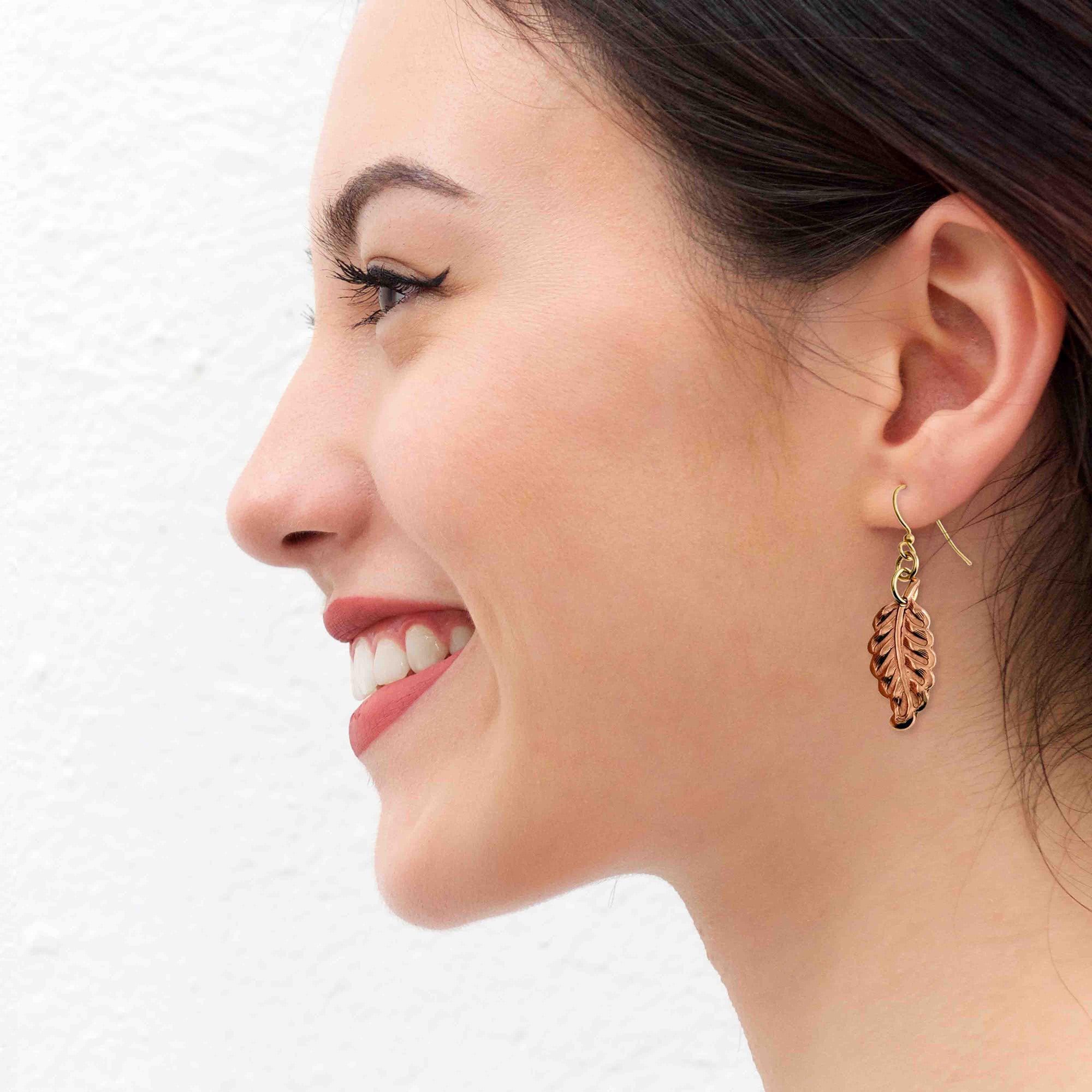 Woman wearing a Small Feather Copper Dangle Earring on a white background