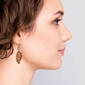 2 of 7: Woman wearing Small Feather Copper Dangle Earrings against a light background