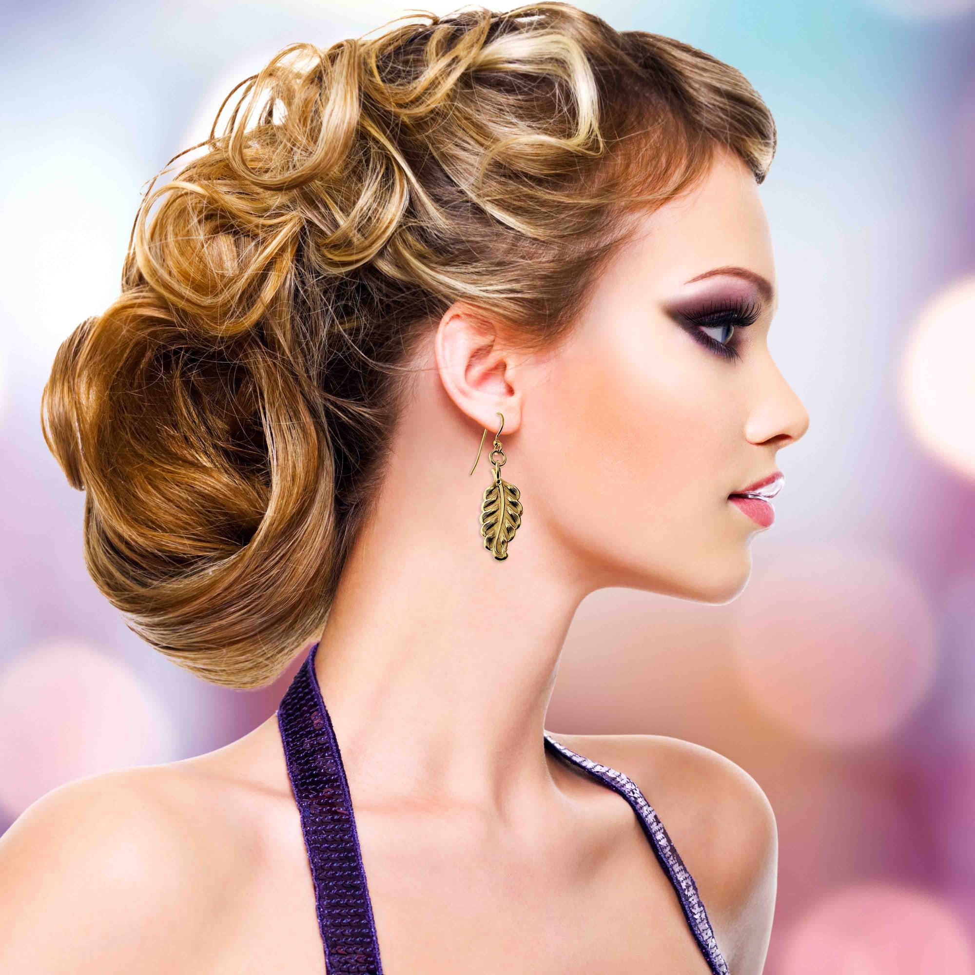 Woman with elegant updo hairstyle against a blurred background wearing Small Feather Nu Gold Brass Dangle Earrings 