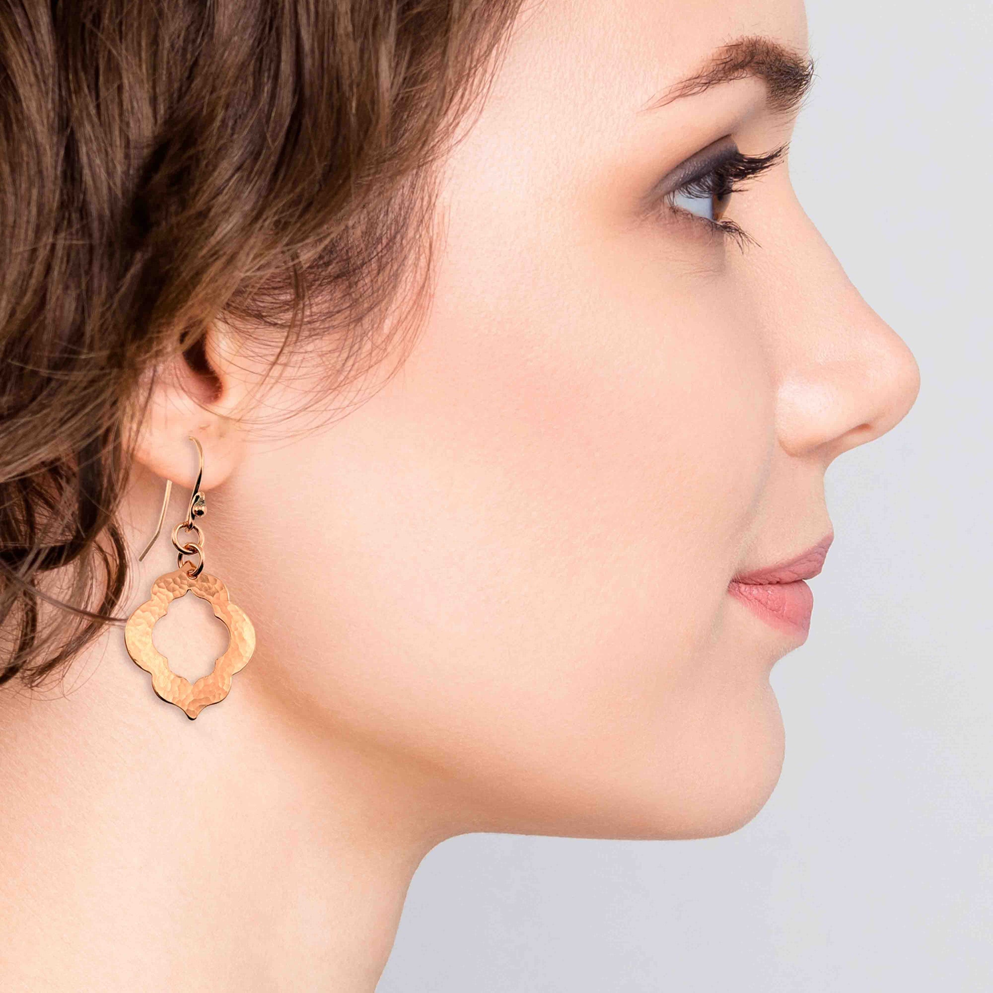 A Chic Woman Wearing Small Hammered Copper Pierced Quatrefoil Dangle Earrings