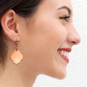 5 of 7: A Smiling Woman Wearing Small Hammered Copper Quatrefoil Dangle Earrings