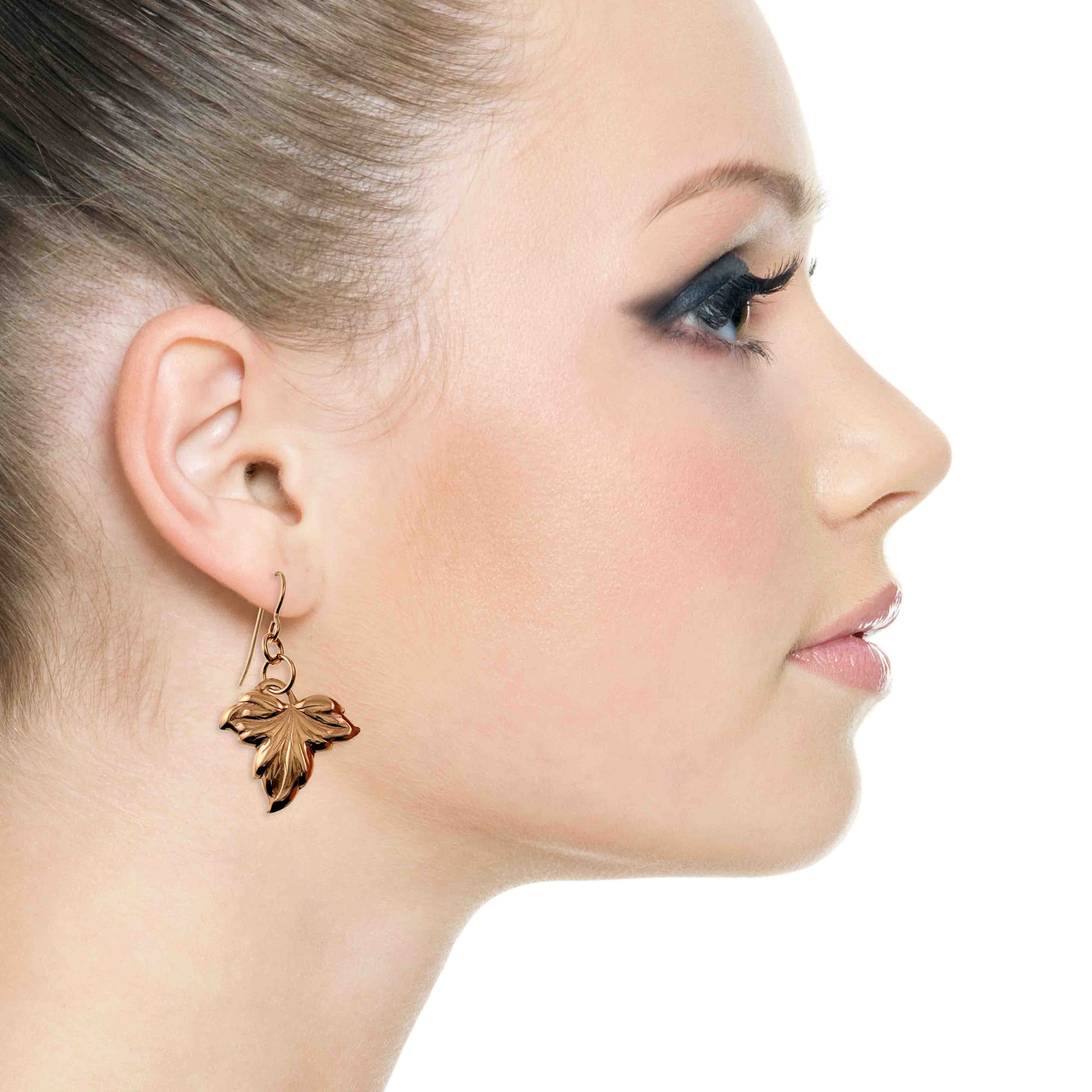 Close-up of a woman wearing a Small Maple Leaf Bronze Dangle Earring on a white background