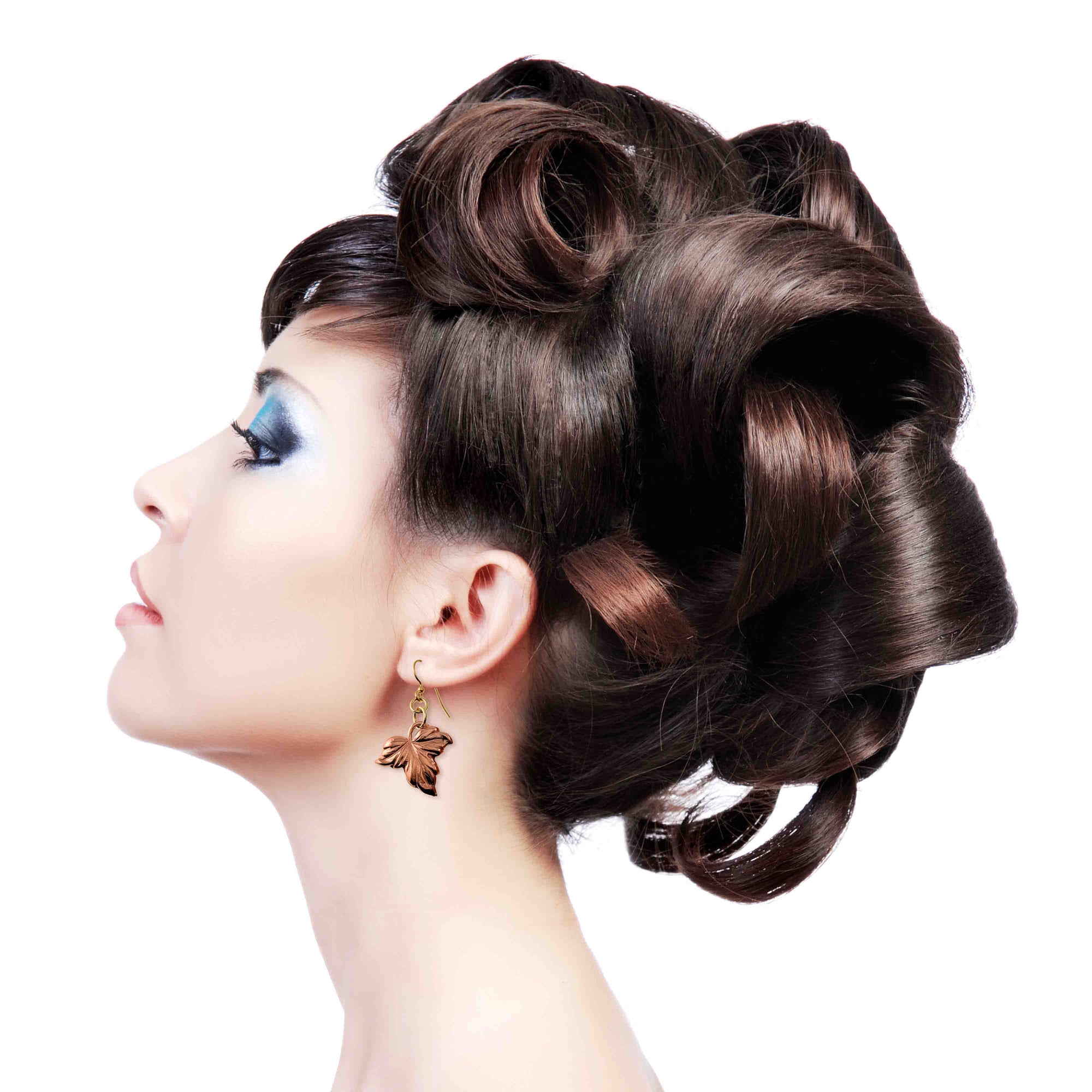 Woman with an elaborate brown hair updo on a white background wearing Small Maple Leaf Copper Dangle Earrings