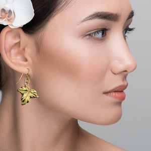 2 of 7: Close-up of a woman wearing Small Maple Leaf Nu Gold Brass Dangle Earrings  with a gray background