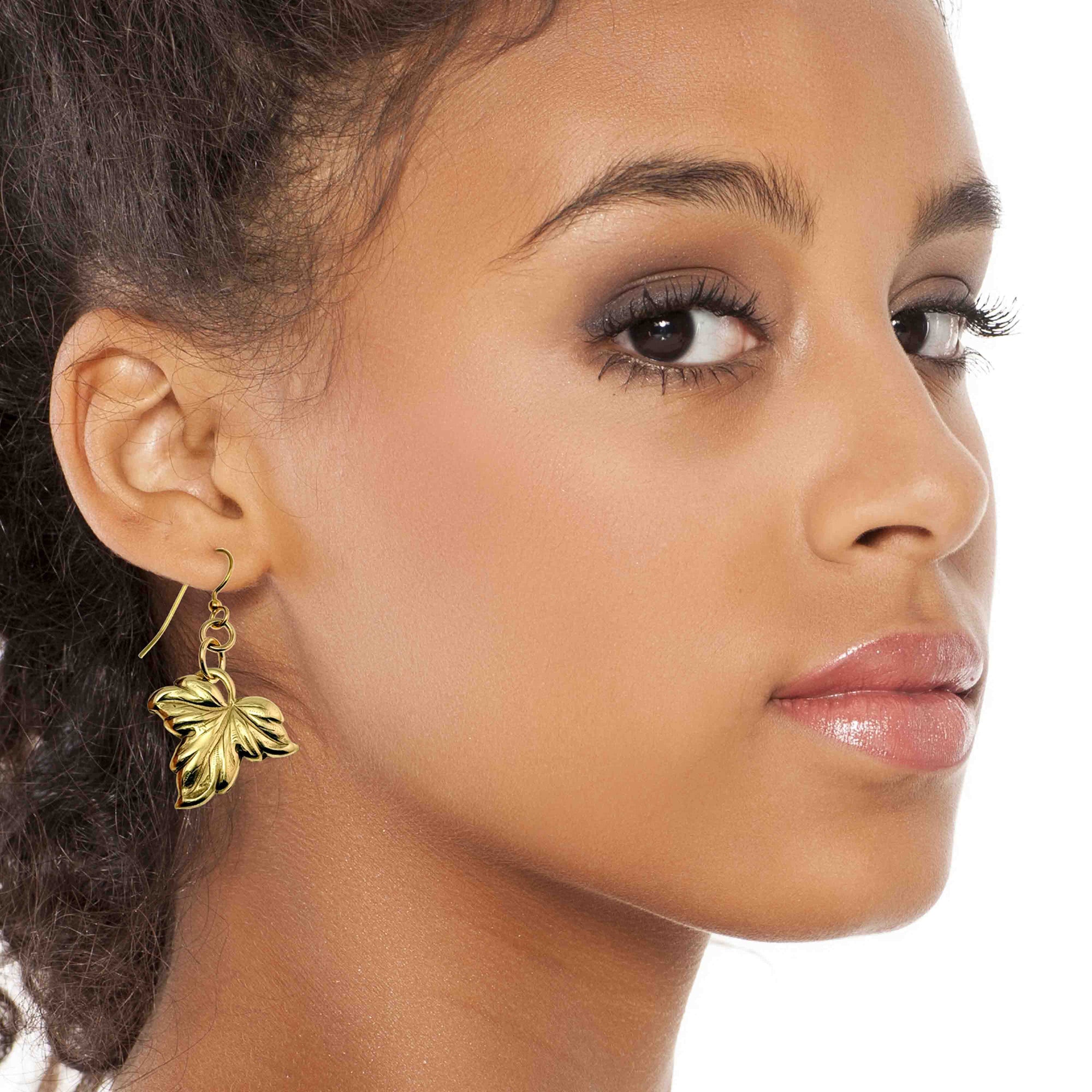 Close-up of a woman wearing a Small Maple Leaf Nu Gold Brass Dangle Earring on a white background