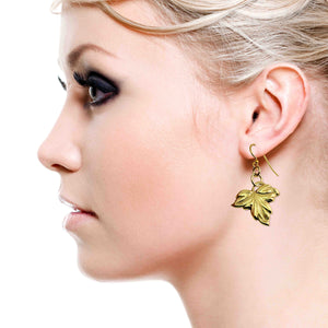 6 of 7: Close-up of a woman with blonde hair  wearing Small Maple Leaf Nu Gold Brass Dangle Earring  on a white background