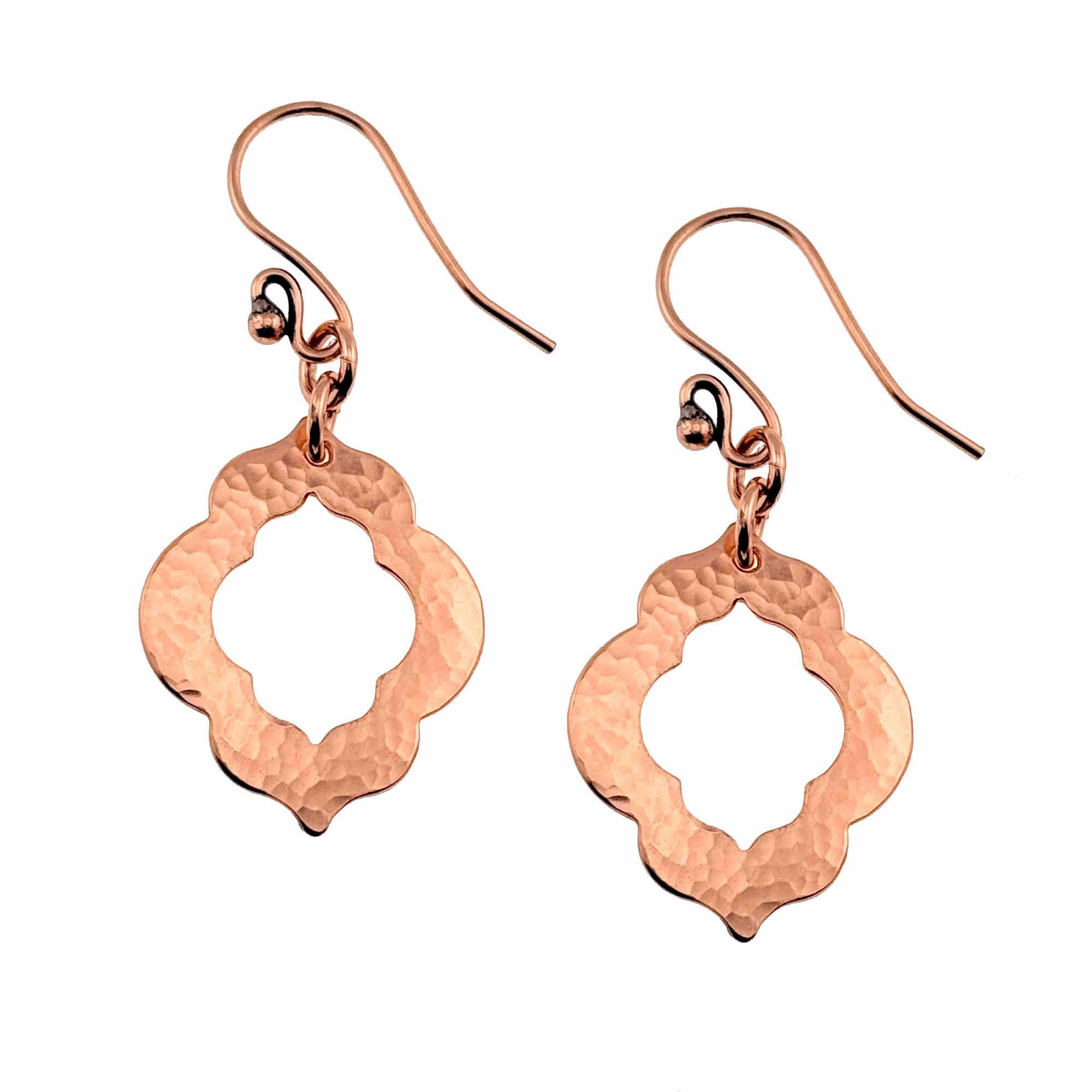 A Pair of Small Hammered Copper Pierced Quatrefoil Dangle Earrings on a White Background