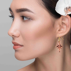 2 of 7: Close-up of a woman wearing a Star of Bethlehem Copper Dangle Earring with a gray background