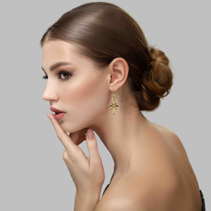 2 of 7: Woman wearing Star of Bethlehem Nu Gold Brass Dangle Earrings against a gray background