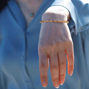 4 of 8: A Woman wearing a 3mm Twisted Copper Cuff Bracelet  on her wrist with a blurred blue background