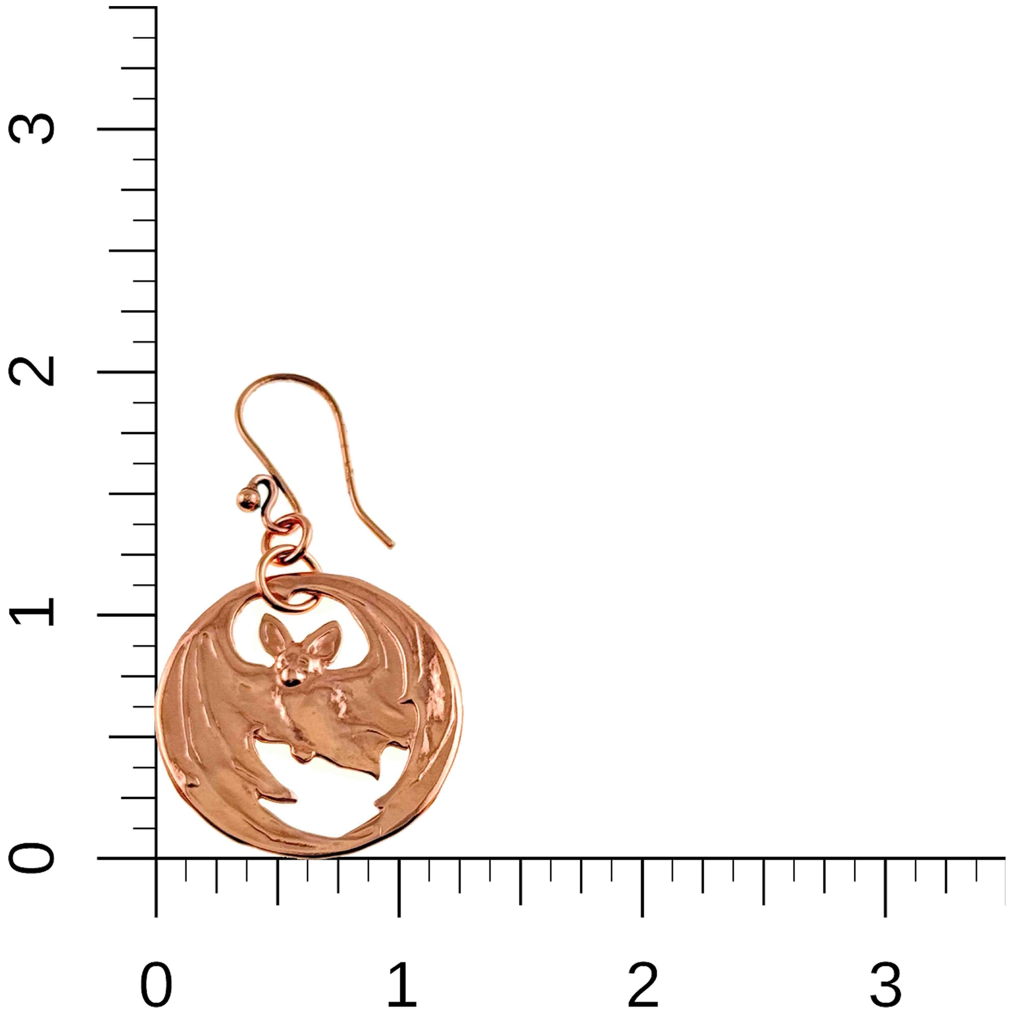 Vampire Bat Copper Disc Earring on a white background with a ruler for scale.