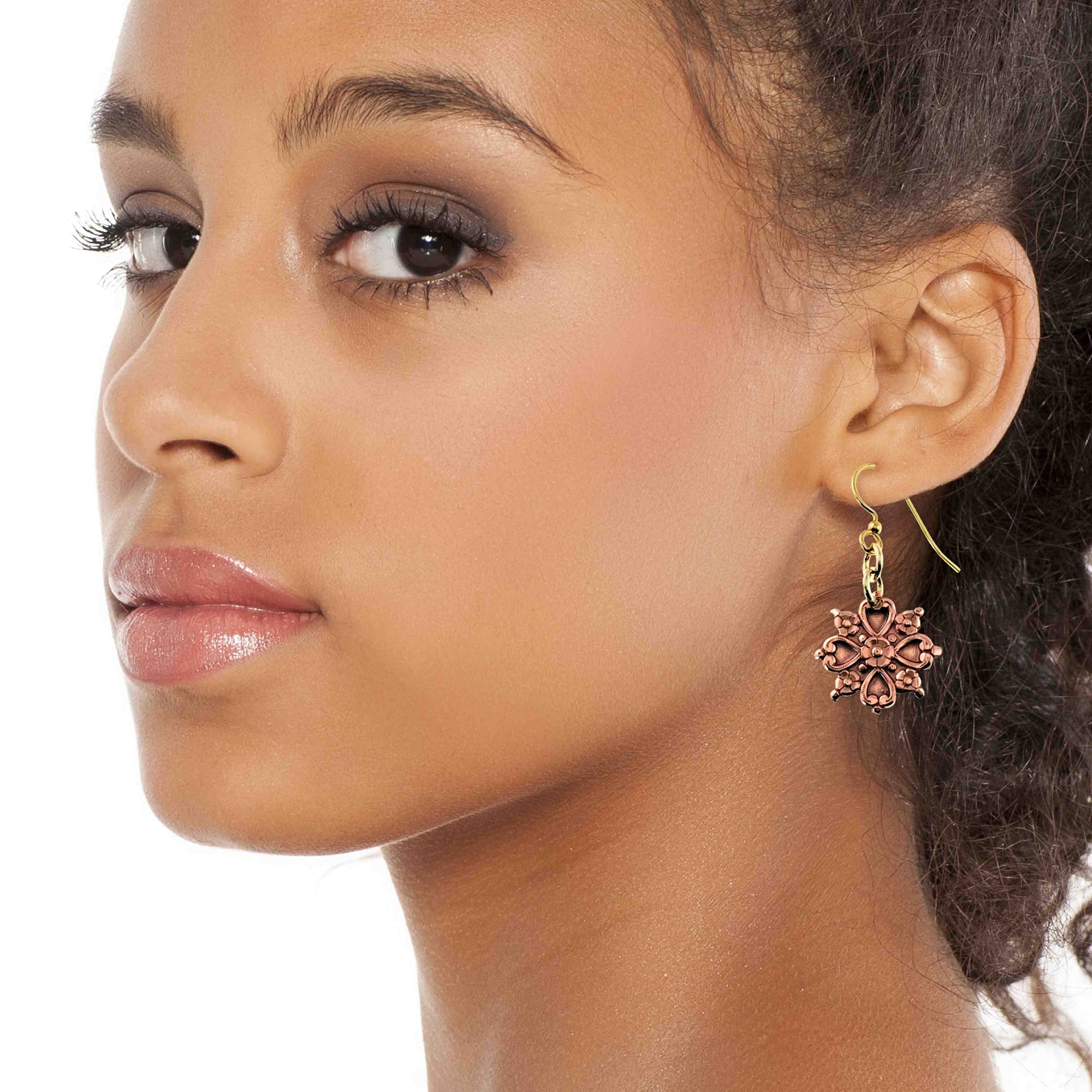 Close-up of a woman wearing a Victorian Copper Snowflake Dangle Earring on a white background