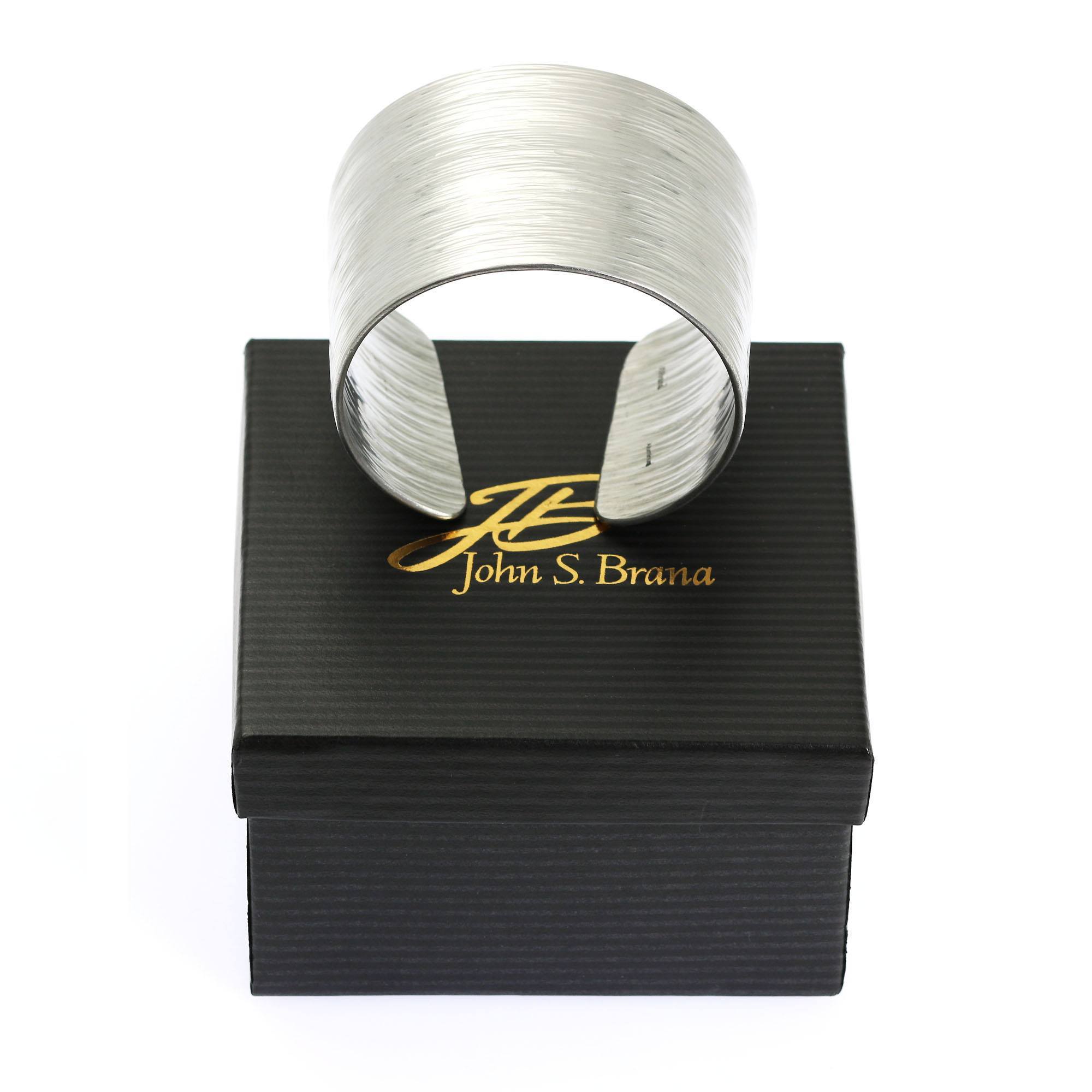 Aluminum Bark Cuff on top of a Black Gift Box with Gold Logo