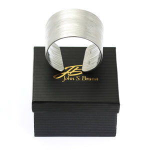 6 of 6: Aluminum Bark Cuff on top of a Black Gift Box with Gold Logo