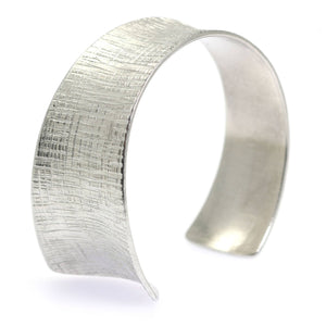 1 of 7: An Anticlastic Tapered Linen Aluminum Bangle Bracelet on a White Background