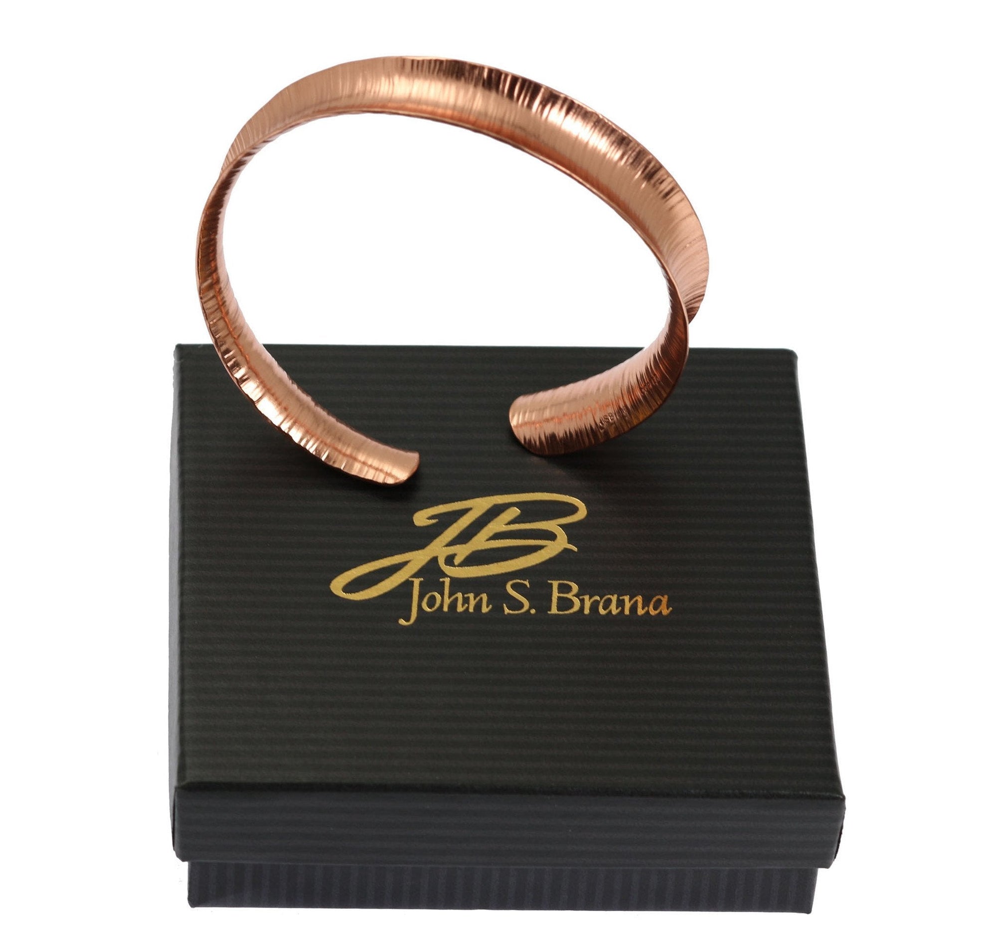 Chased Anticlastic Copper Bangle Bracelet on top of a Black Gift Box with Gold Logo