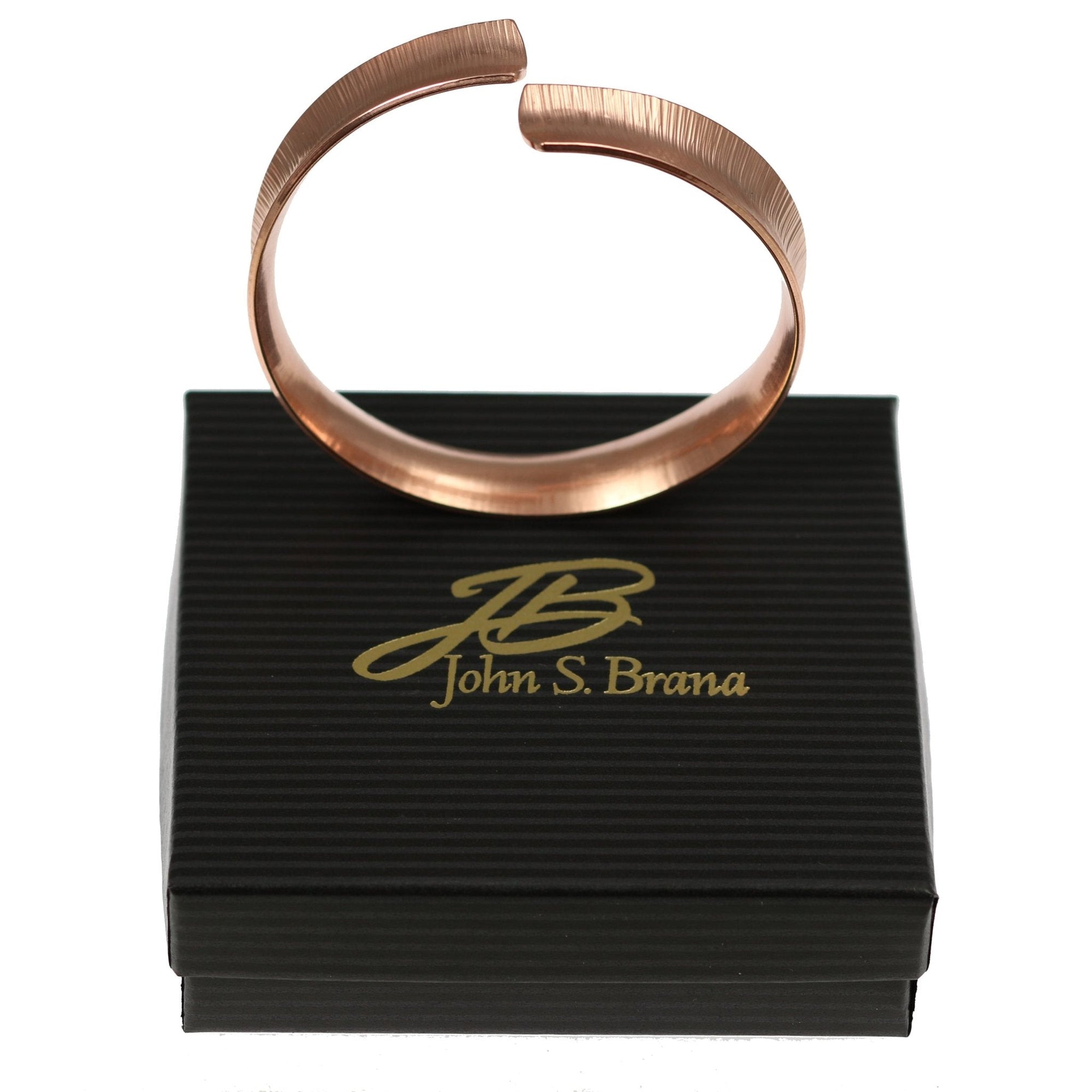 Chased Copper Bangle Bracelet on top of a Black Gift Box with Gold Logo