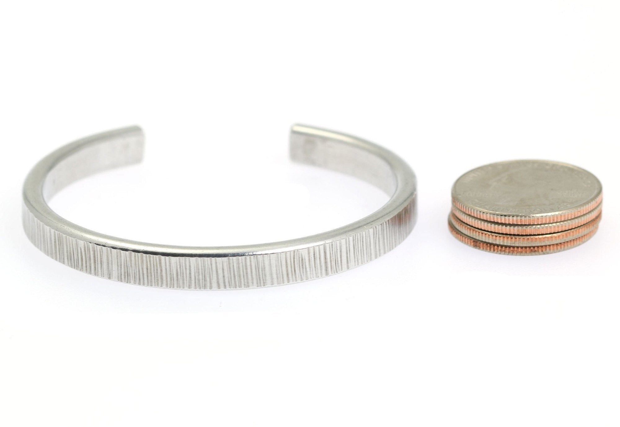 Width of Thin Chased Aluminum Cuff Bracelet compared to a stack of 4 US Quarter Coins