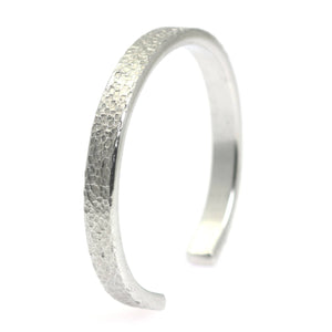 1 of 7: A Thin Texturized Aluminum Cuff Bracelet on a White Background